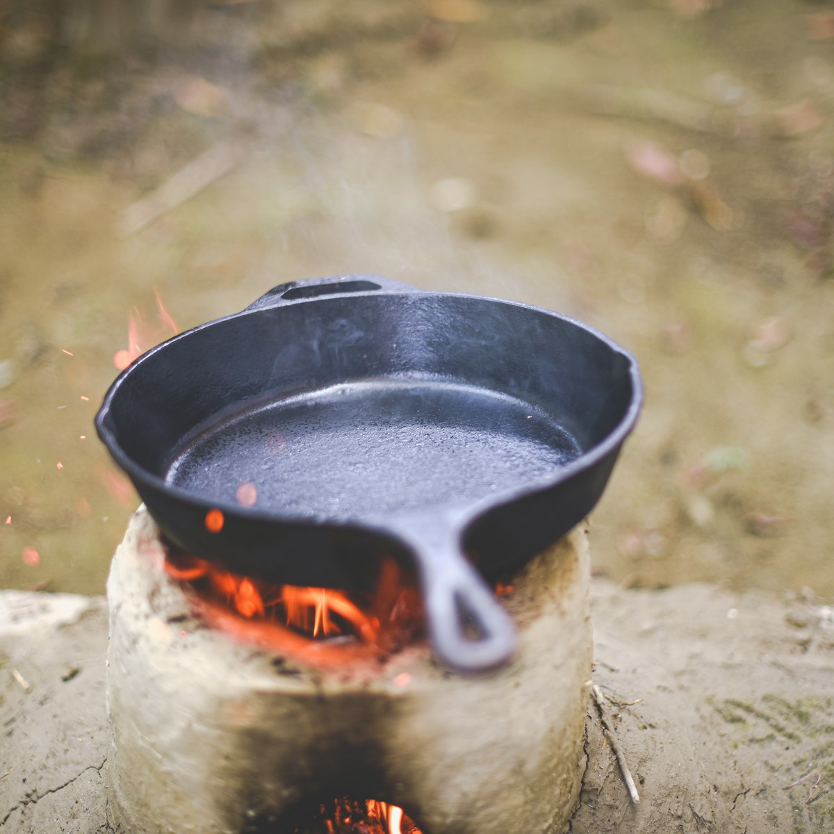 Cast iron cookware set being used for outdoor cooking over a campfire